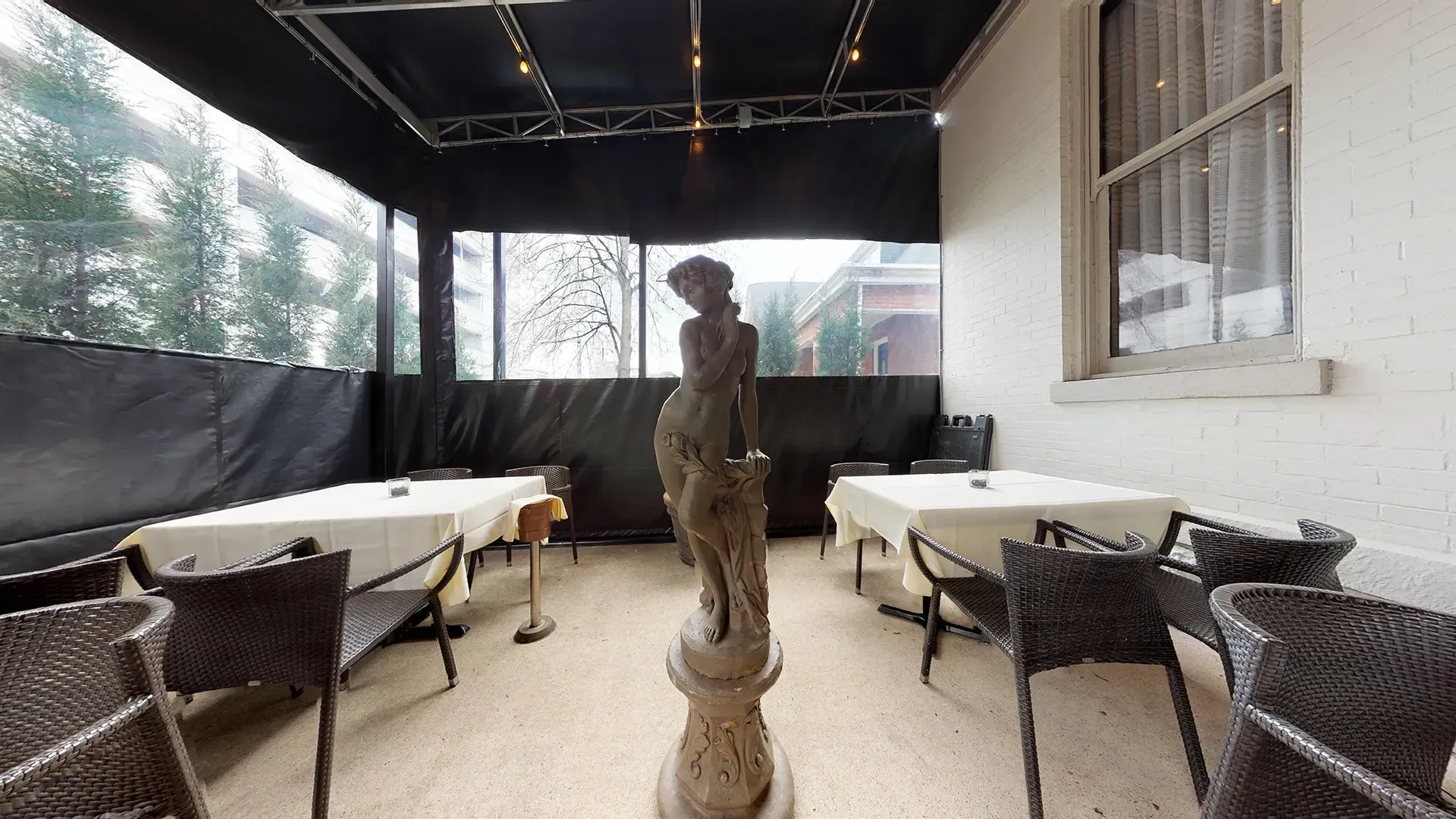 A patio with tables and chairs and a statue in the middle
