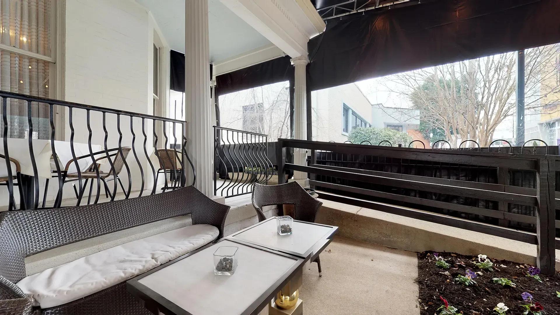 A porch with a couch , table , chairs and a railing.