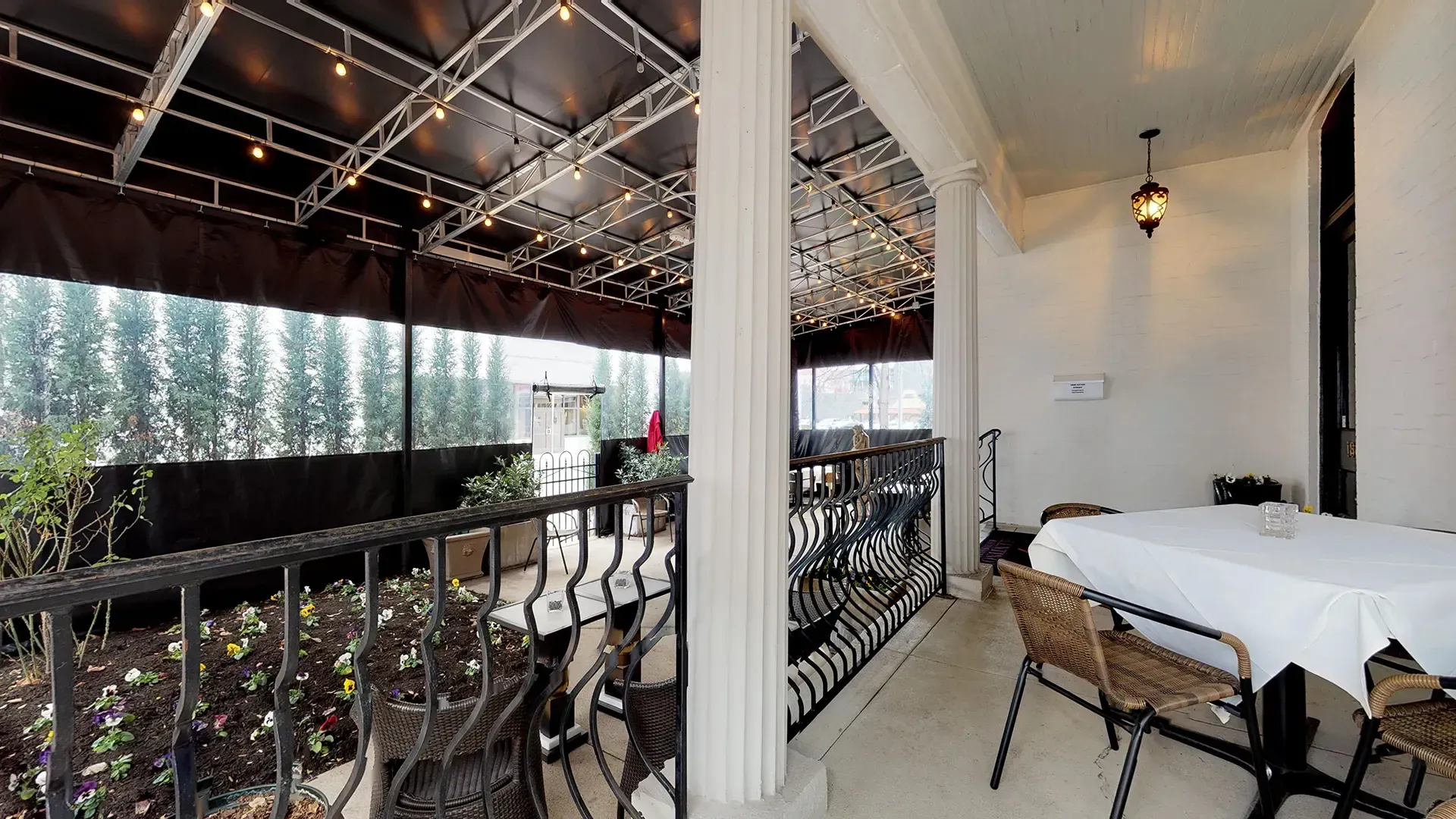 A balcony with a table and chairs under a canopy