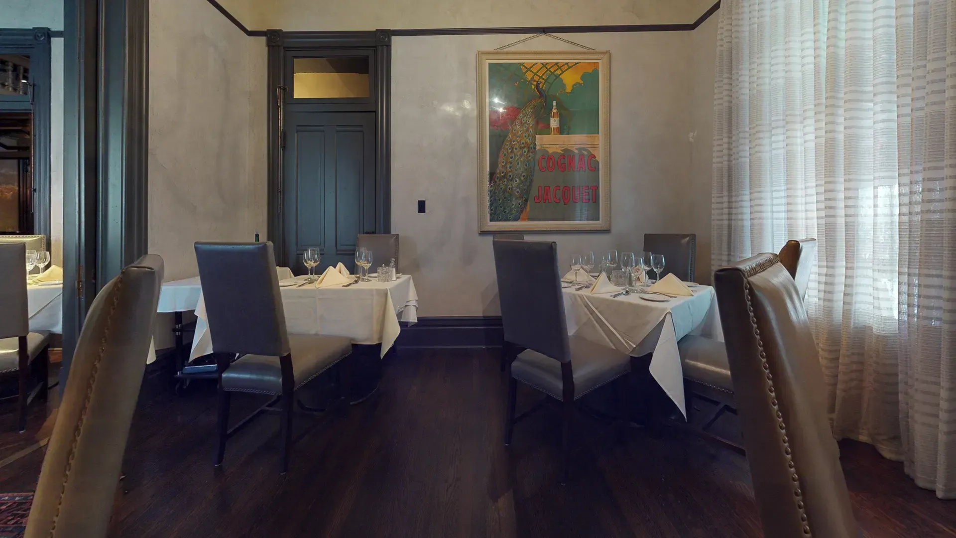 A dining room with tables and chairs and a painting on the wall.