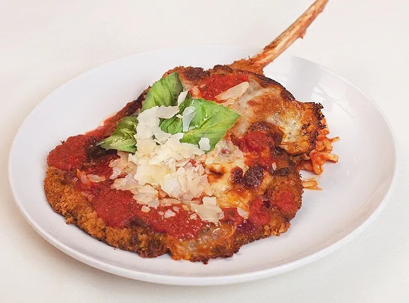 A white plate topped with a piece of Veal Parmesean