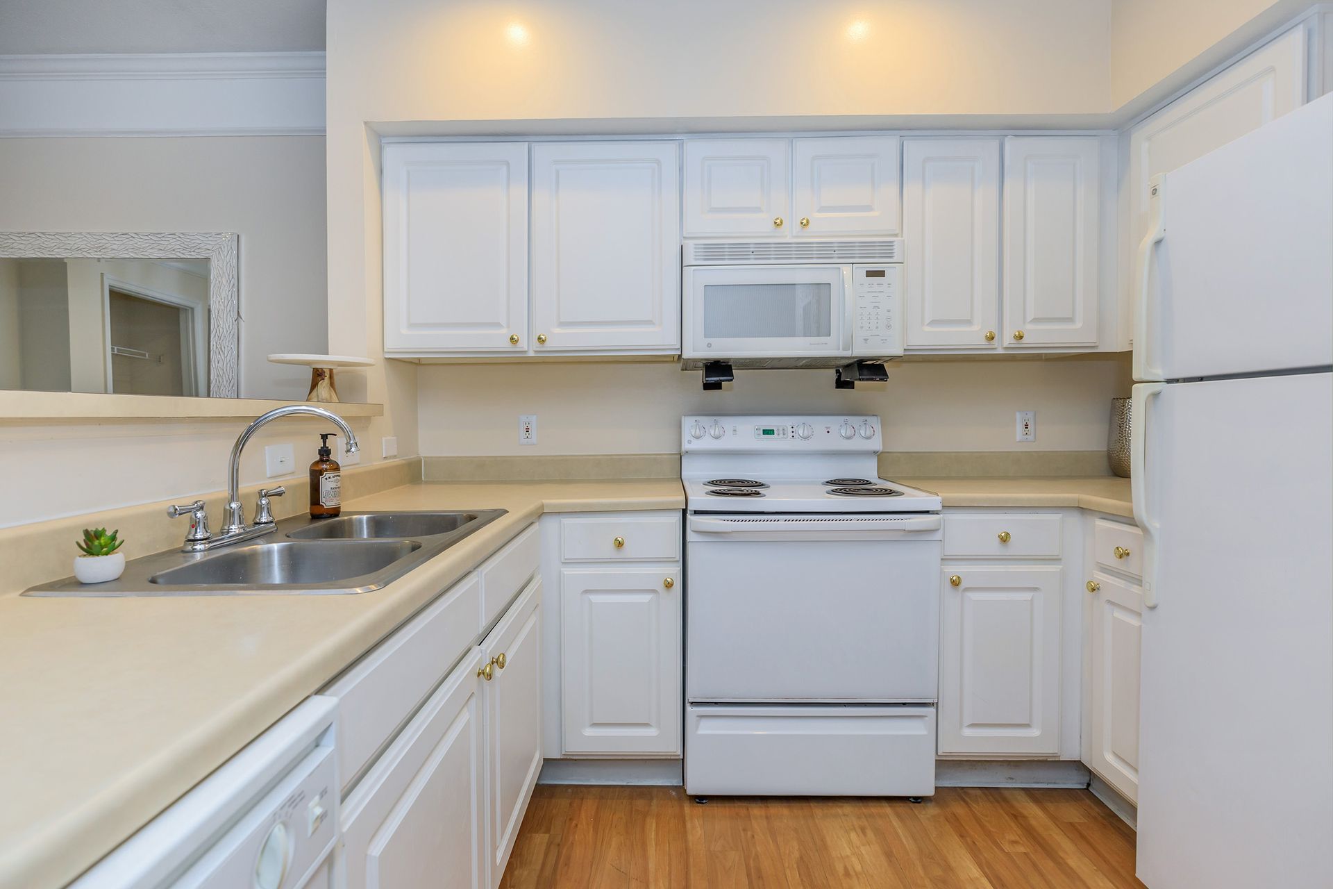 White kitchen with white appliances, tan countertops, and light wood flooring at Quarry in Columbus, OH.