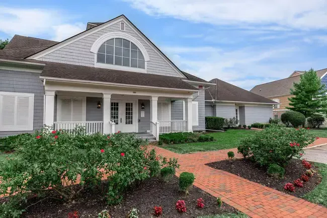 A two-story, grey-sided building with a brick walkway and landscaped garden under a blue sky at Quarry in Columbus, OH.