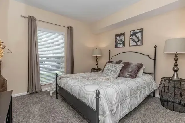 Bedroom with a bed, two nightstands, window with blinds, and neutral color scheme at Quarry in Columbus, OH.