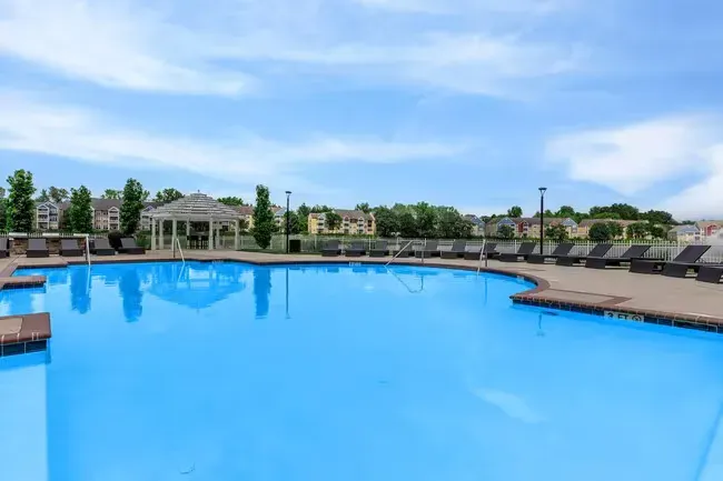 Bright blue pool with lounge chairs, gazebo, and cloudy blue sky in the background at Quarry in Columbus, OH.