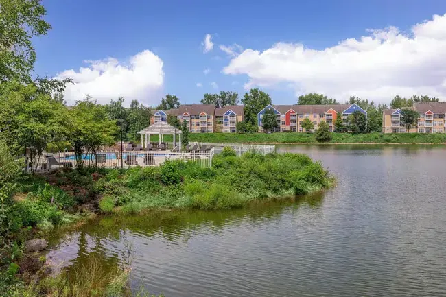 Lakeside apartment complex with gazebo, lush greenery, and blue sky at Quarry in Columbus, OH.