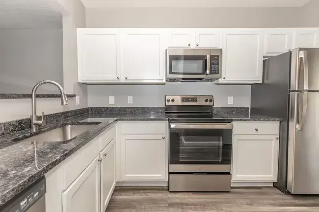 White kitchen with stainless steel appliances and gray countertops at Quarry in Columbus, OH.