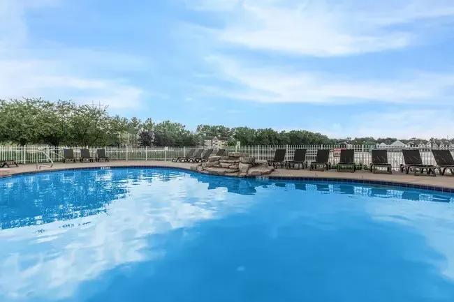 Blue swimming pool with lounge chairs on the side under a partly cloudy sky  at Quarry in Columbus, OH.
