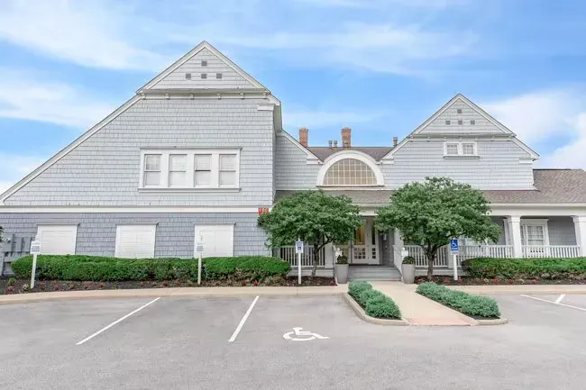 Gray building with parking in front, green hedges, blue sky at Quarry in Columbus, OH.