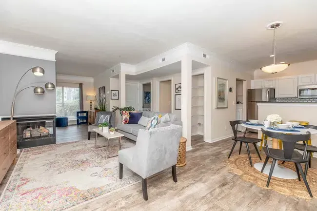 Living room with gray walls, sofa, armchair, fireplace, and dining area at Quarry in Columbus, OH.