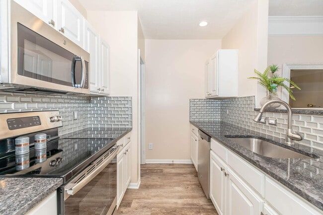 Modern kitchen with white cabinets, stainless steel appliances, and gray countertops and backsplash at Quarry in Columbus, OH.