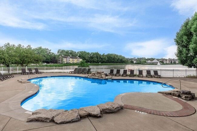 Pool with blue water and lounge chairs, surrounded by a concrete deck, trees, and cloudy sky at Quarry in Columbus, OH.