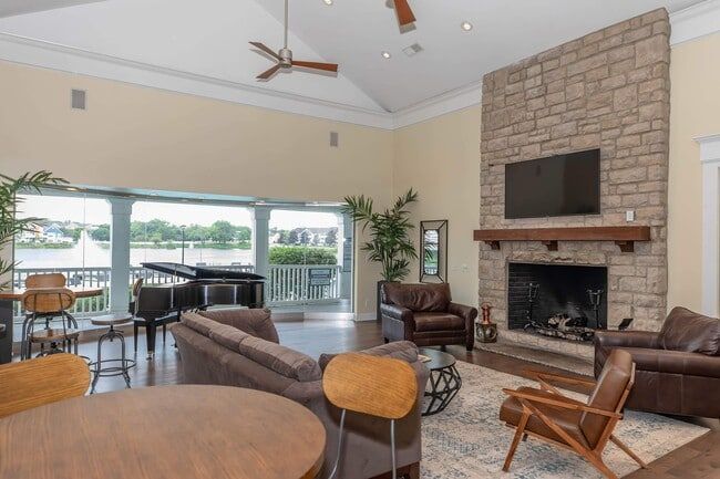 Spacious living room with fireplace, water view, grand piano, seating, and ceiling fans  at Quarry in Columbus, OH.