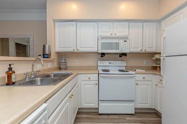 White kitchen with white appliances, tan countertops, and light wood flooring at Quarry in Columbus, OH.