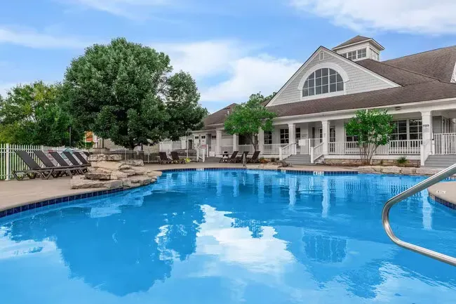 Swimming pool in front of a white building with chairs, green trees, and blue sky at Quarry in Columbus, OH.