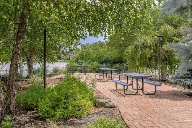Picnic area with brick pathway, picnic tables, trees, and greenery at Quarry in Columbus, OH.