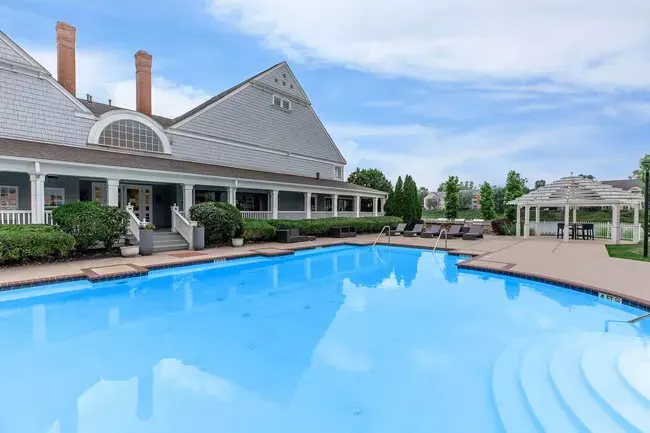 Swimming pool with clubhouse and gazebo on a sunny day. Blue water reflects the sky at Quarry in Columbus, OH.