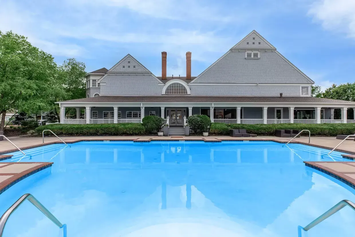 Swimming pool in front of a gray building with two pyramid-shaped roof sections and a covered porch at Quarry in Columbus, OH.