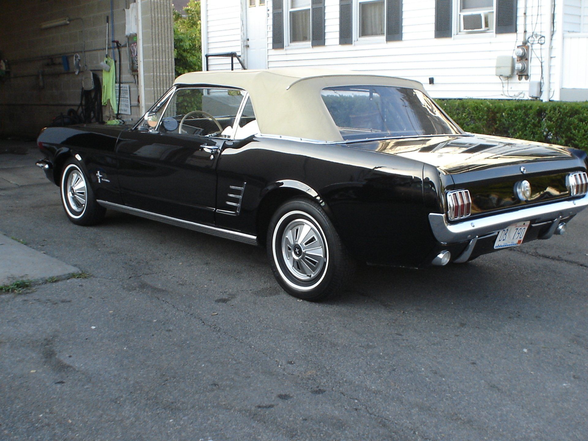 A black mustang convertible is parked in front of a house