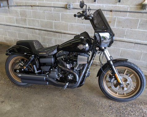A black harley davidson motorcycle is parked in front of a brick wall.