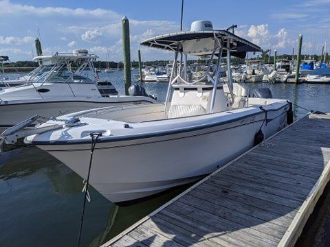A white boat is docked at a dock in a marina.