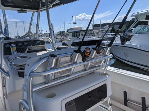 A boat with fishing rods on the back of it is docked in a marina.