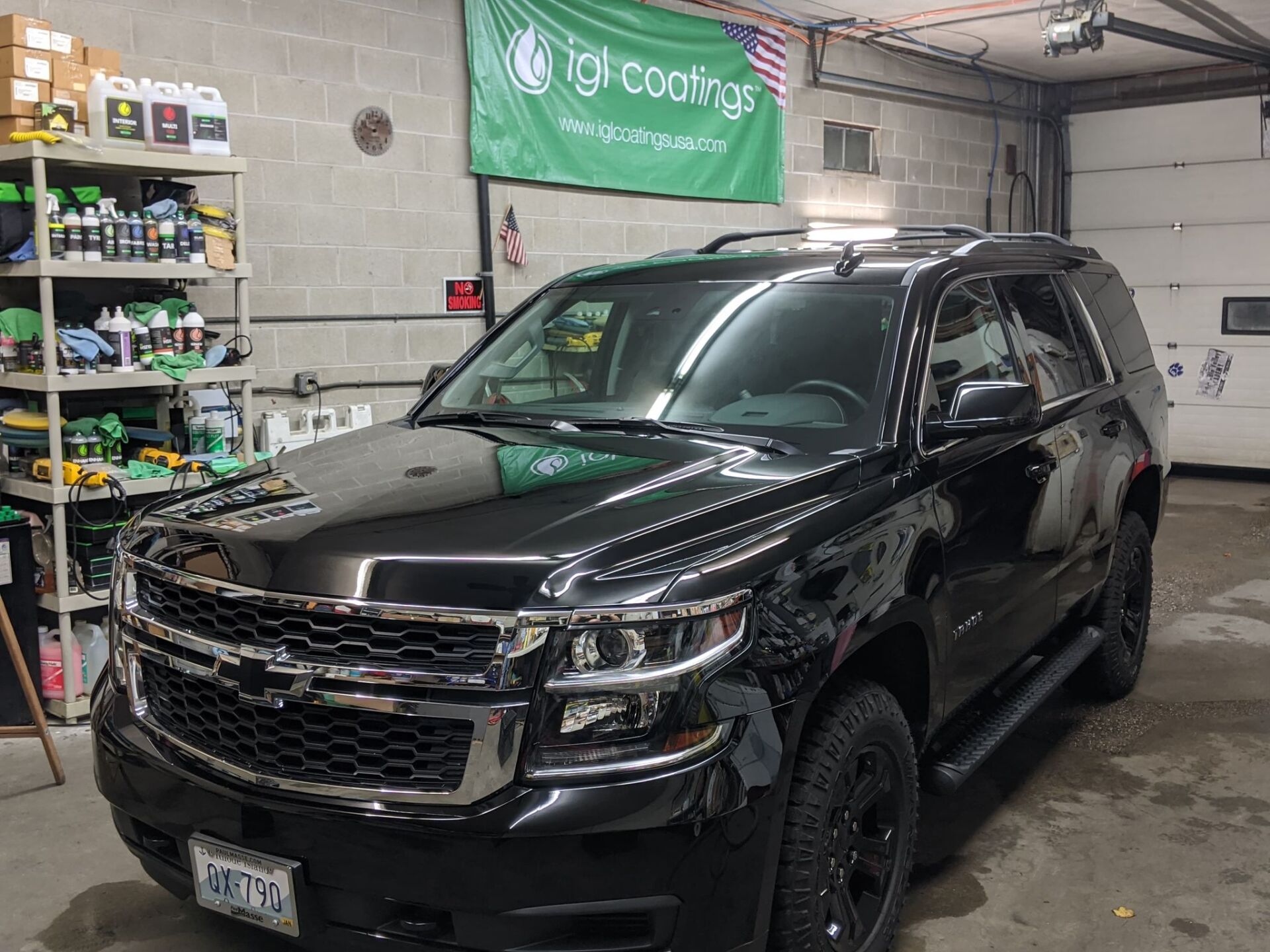 A black suv is parked in a garage next to a green banner.