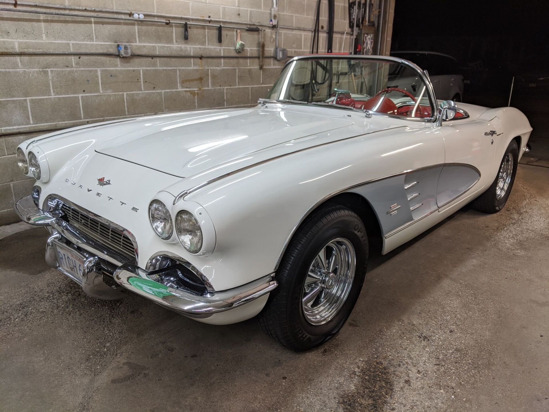 A white corvette convertible is parked in a garage.