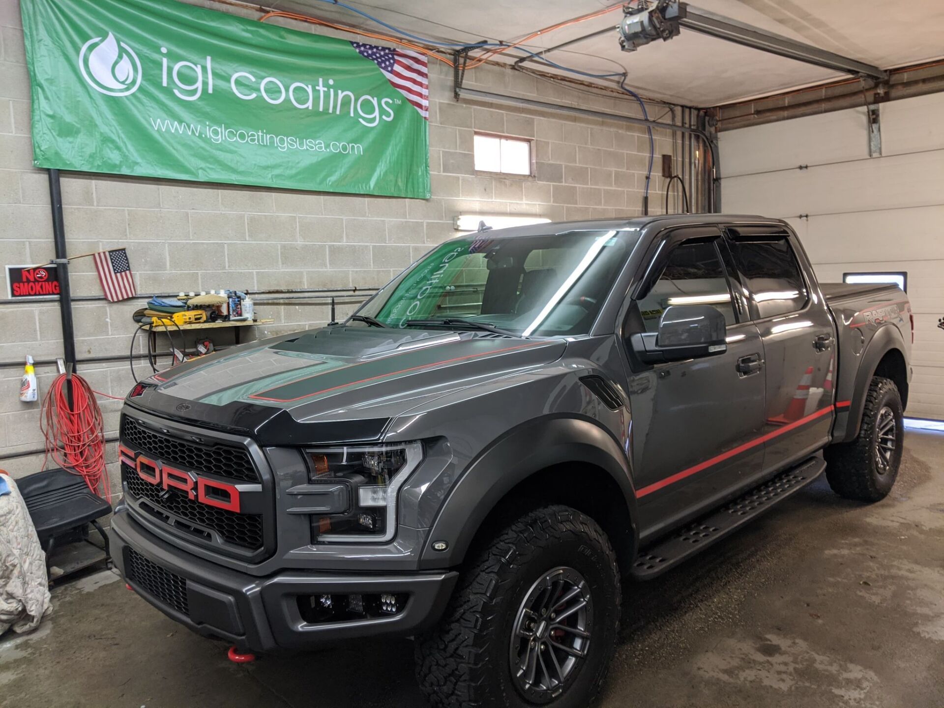 A gray ford raptor truck is parked in a garage.