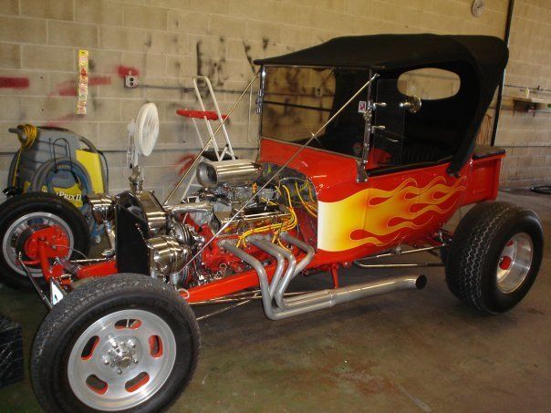 A red car with flames painted on it is parked in a garage