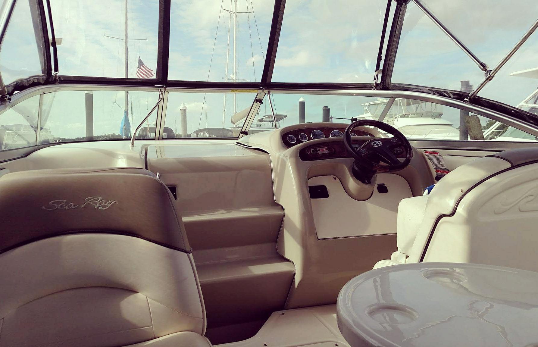 The inside of a boat with a steering wheel and a table