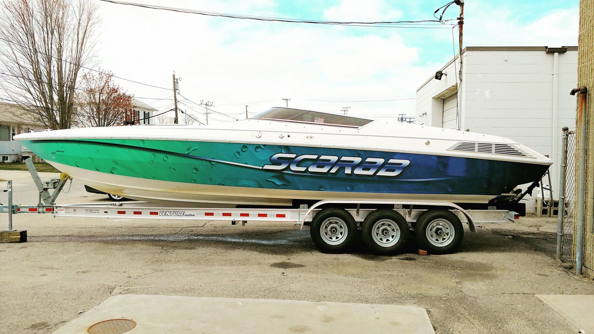 A boat is parked on a trailer in a parking lot.
