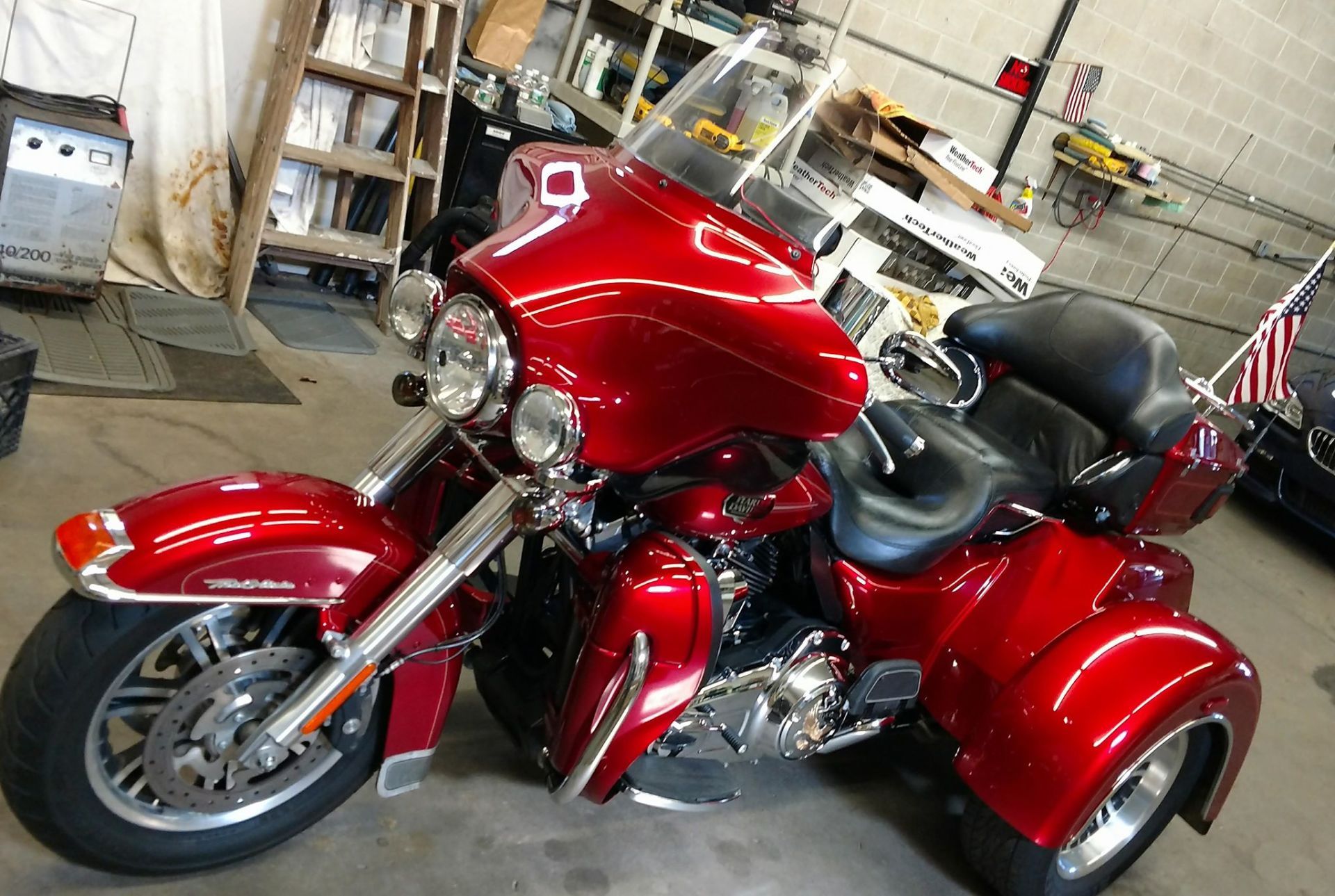 A red motorcycle with three wheels is parked in a garage.
