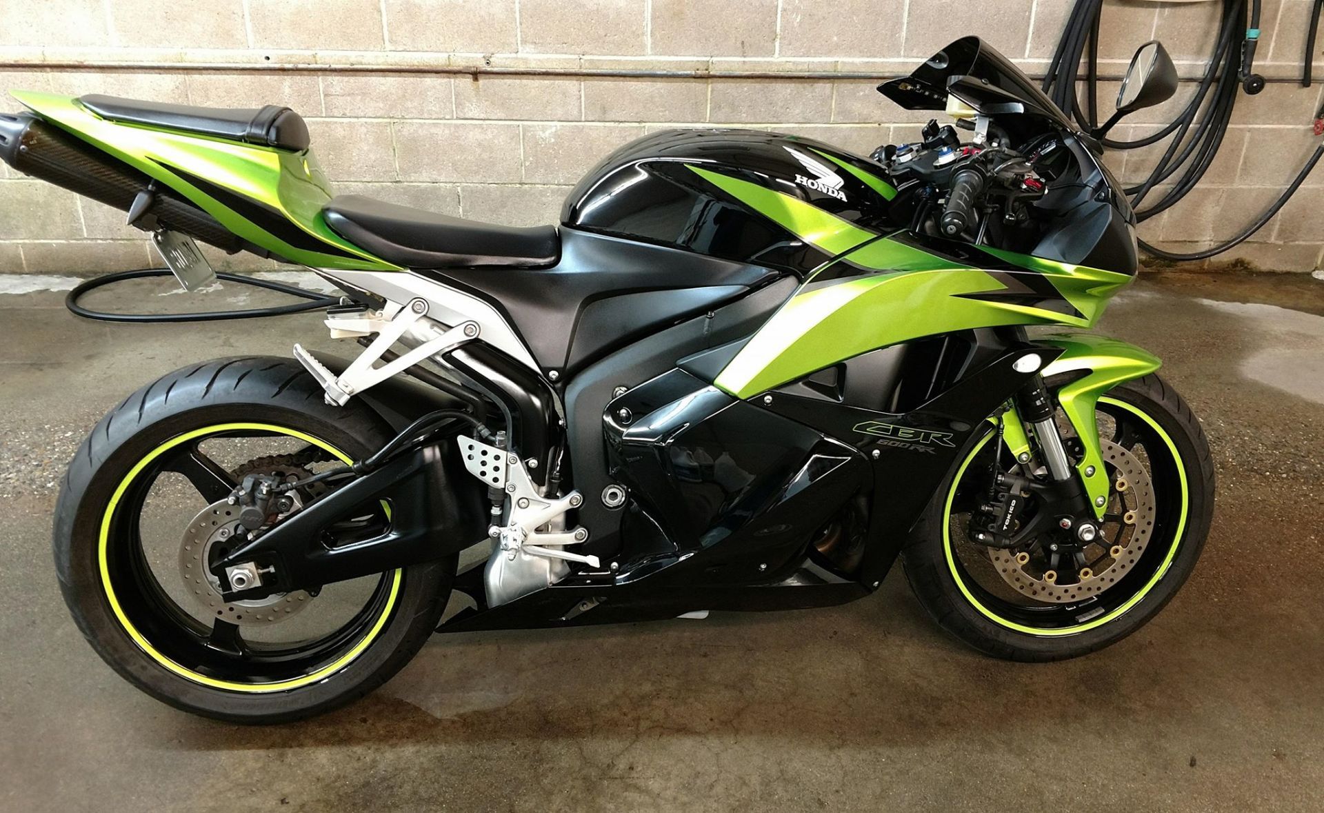 A green and black motorcycle is parked in a garage