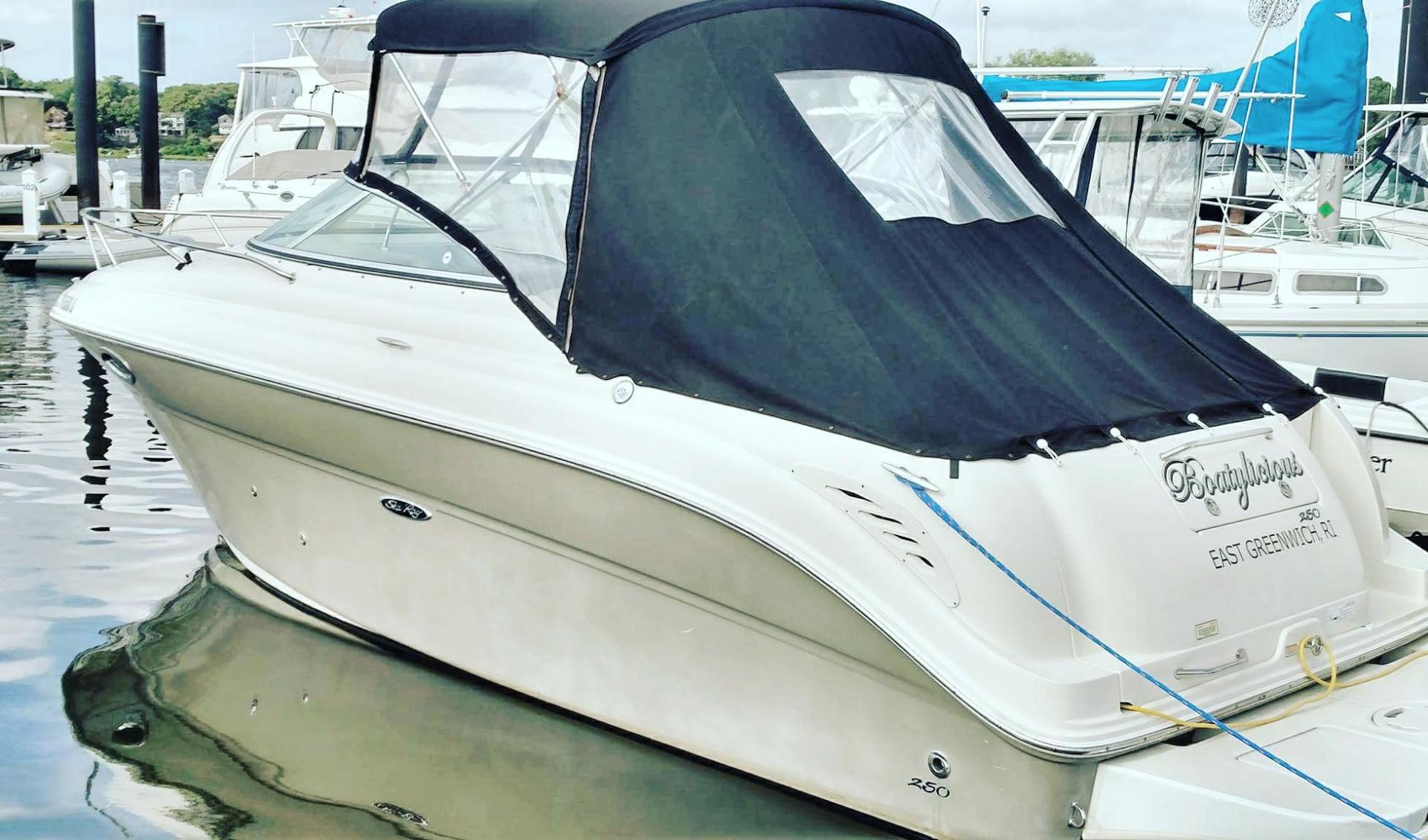 A white boat with a black canopy is docked in a marina.