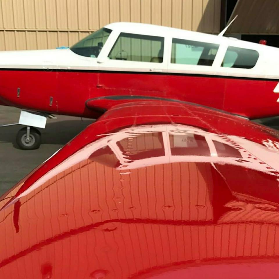 A red and white plane is parked in front of a building