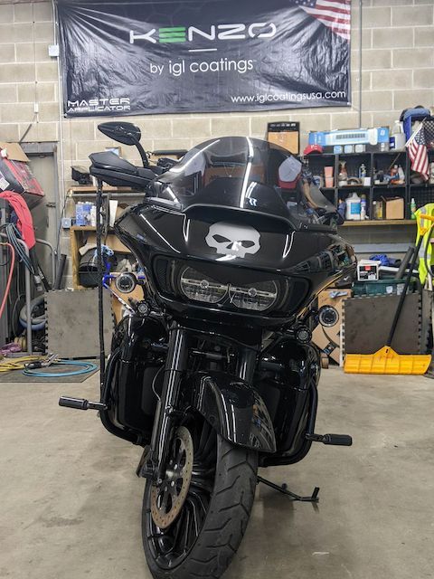 A black motorcycle is parked in front of a kenzo banner