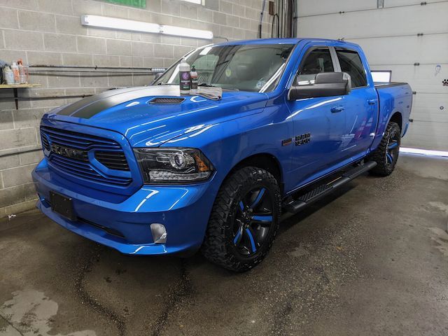 A blue ram truck is parked in front of a garage door.