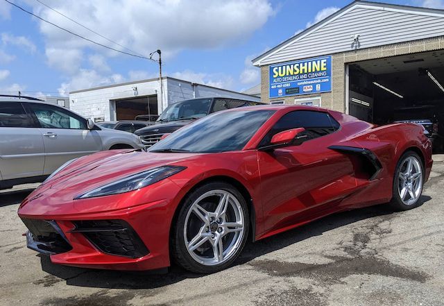A red sports car is parked in front of a car dealership.
