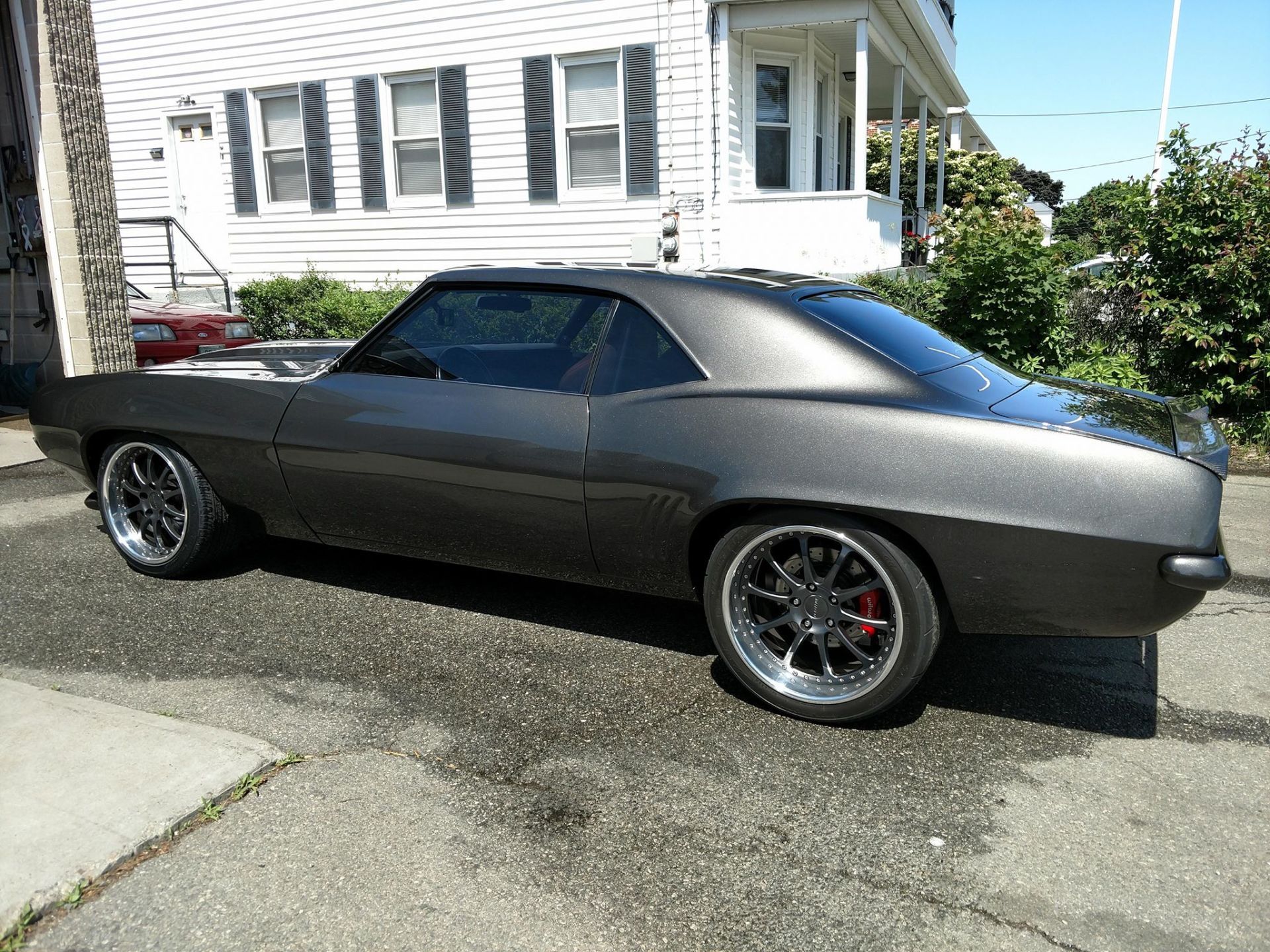 A black car is parked in front of a white house