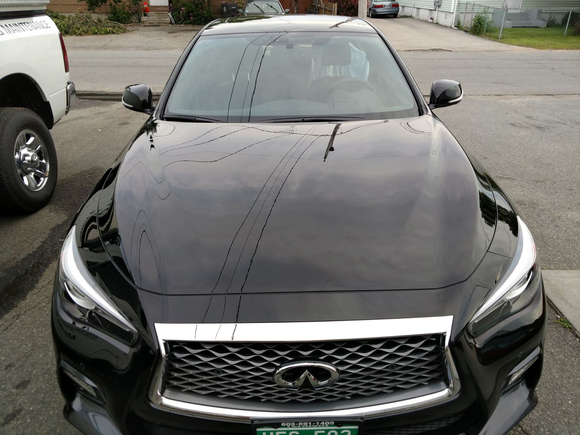 A black infiniti is parked on the side of the road