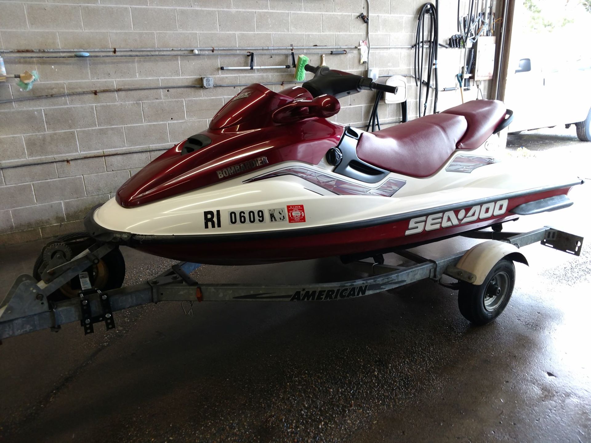 A red and white jet ski is parked on a trailer in a garage.