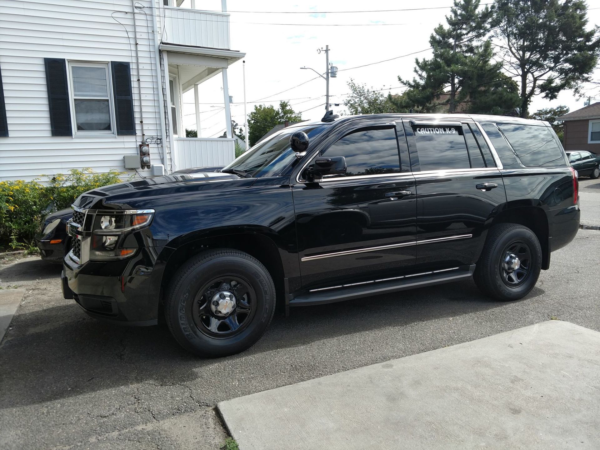 A black suv is parked in front of a house.