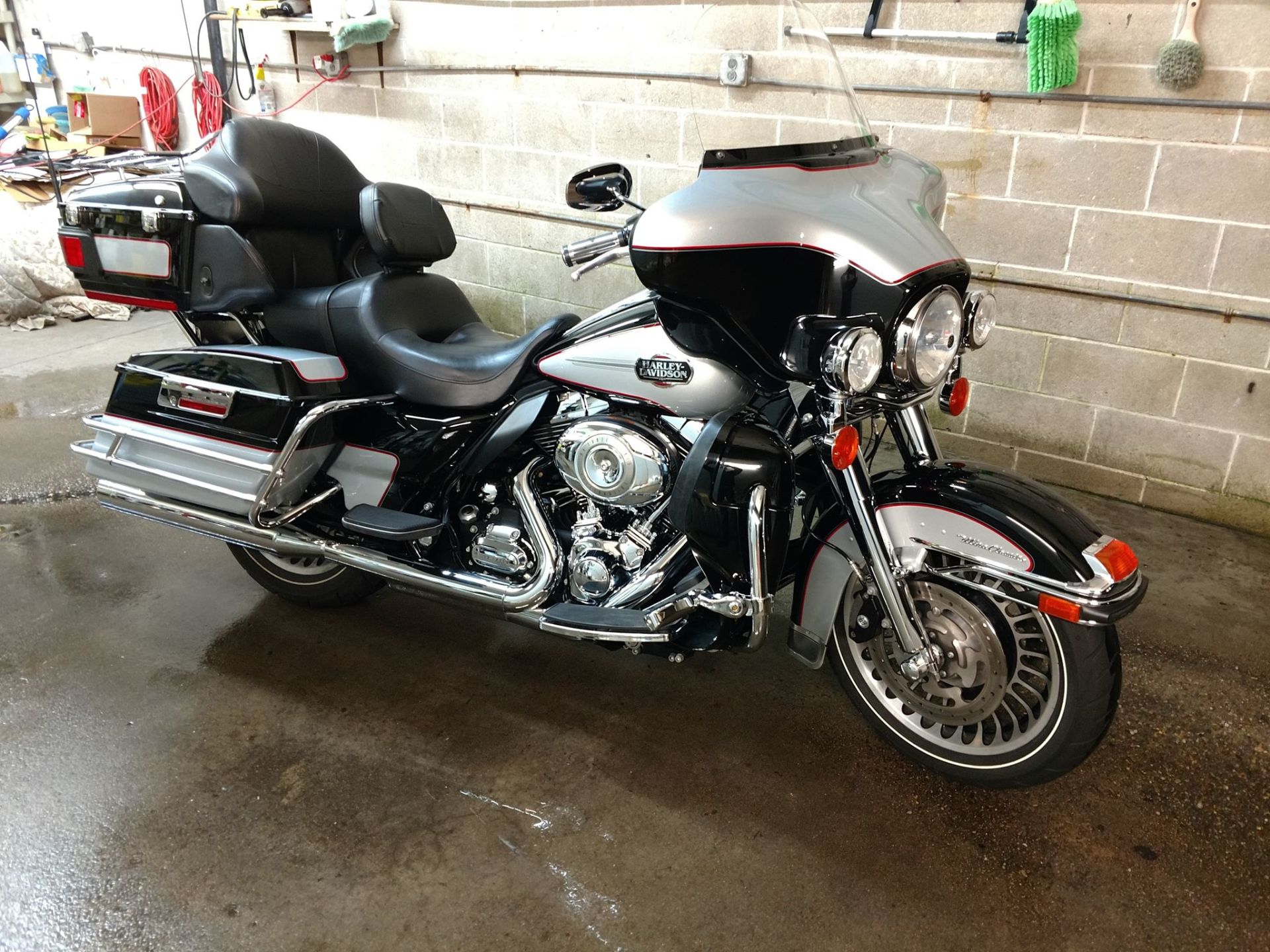 A harley davidson motorcycle is parked in a garage next to a brick wall.
