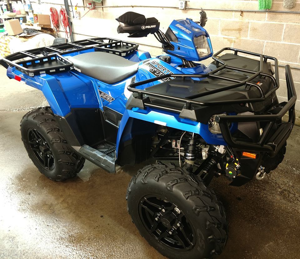 A blue atv with black wheels is parked in a garage