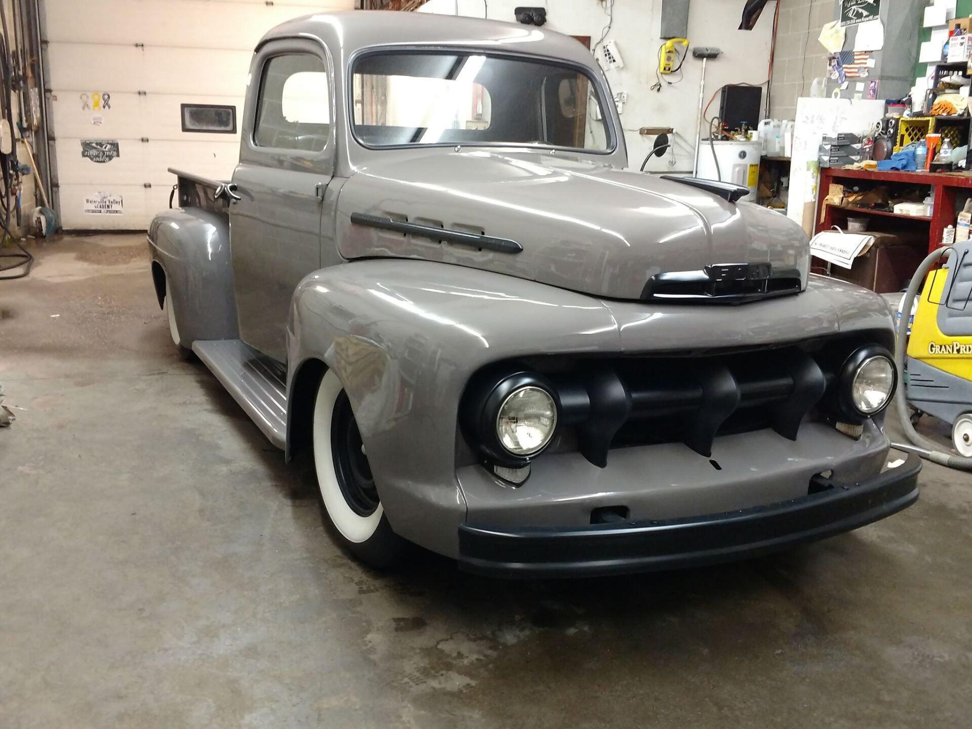 A gray truck is parked in a garage with white tires
