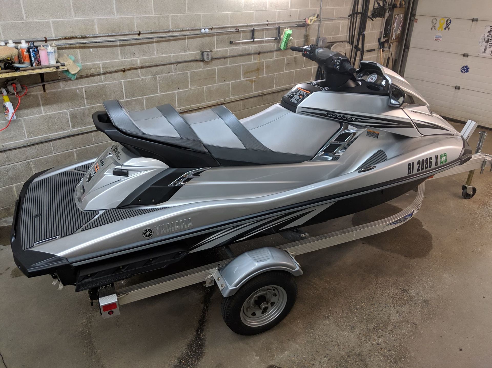 A jet ski is parked on a trailer in a garage.