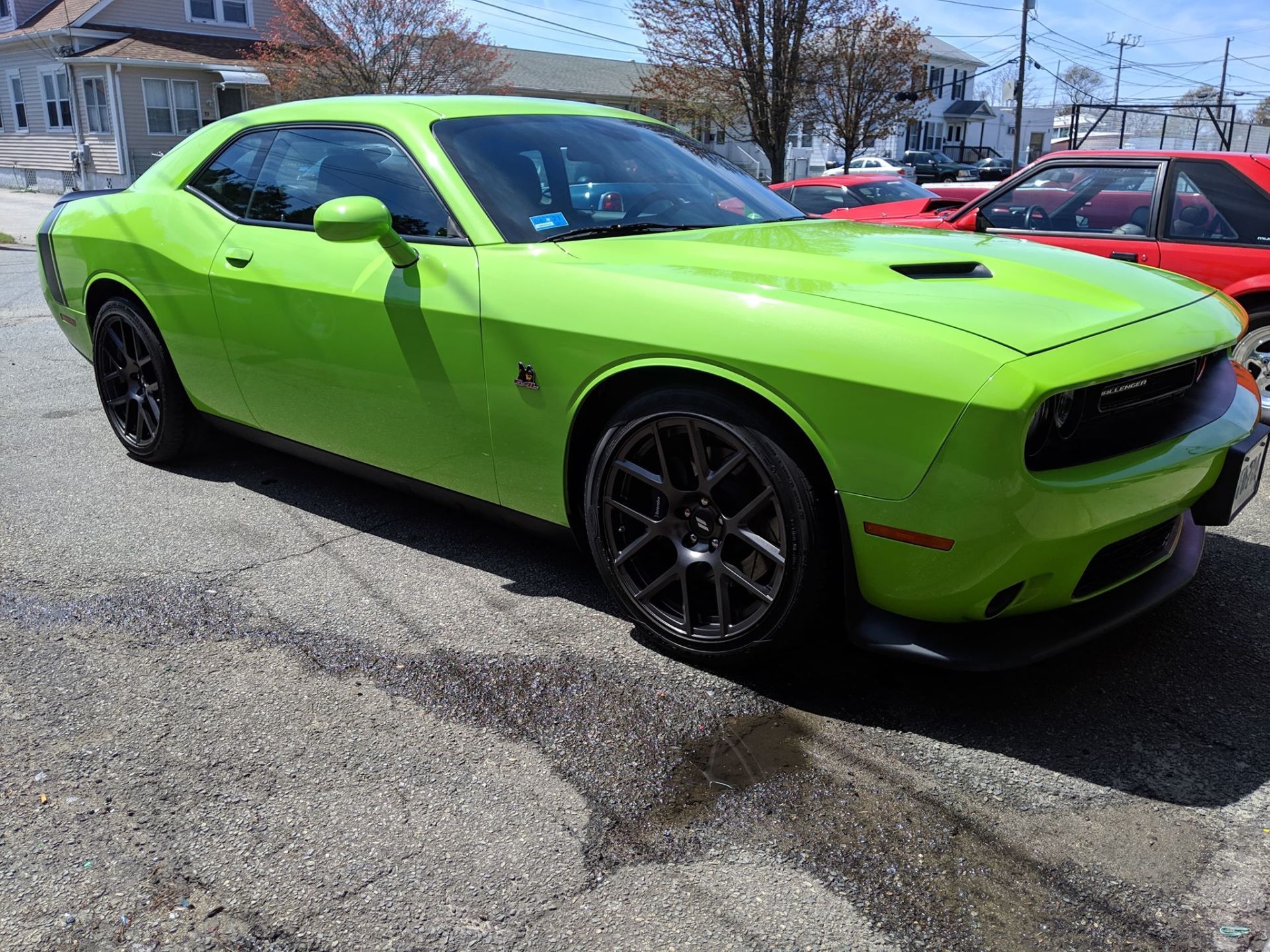 A green dodge challenger is parked on the side of the road.