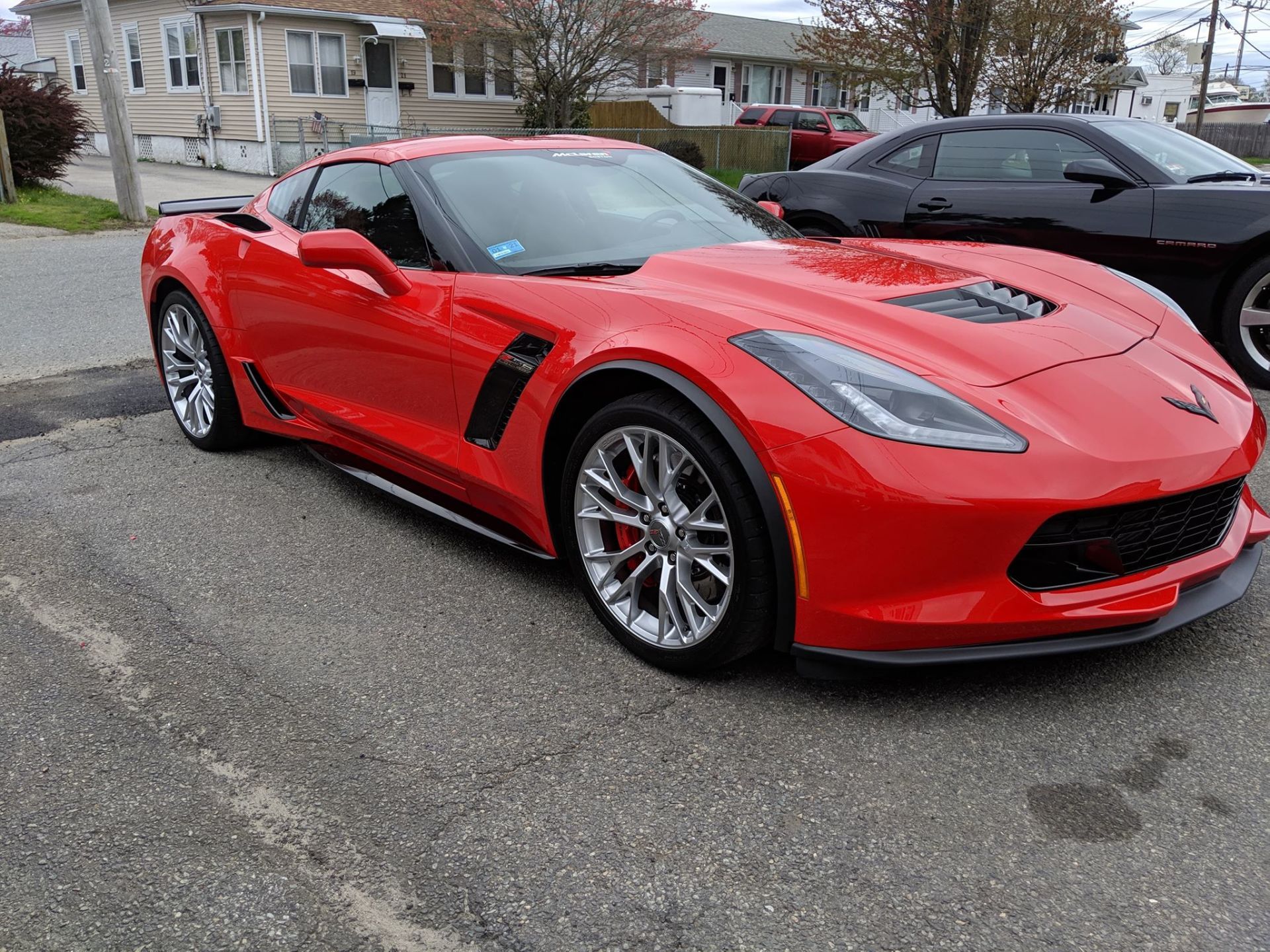A red corvette is parked next to a black corvette in a parking lot.