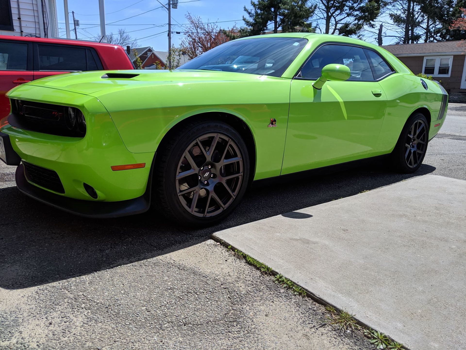 A bright green dodge challenger is parked on the side of the road.